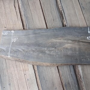 May include: A dark grey wooden slab with natural edges. The slab measures 89 cm long and 25 cm wide. The width is marked as 38 cm. The wood grain is visible.