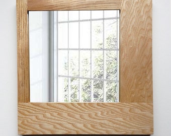 May include: A square mirror with a natural wood frame. The frame has a light wood grain pattern and a simple design.