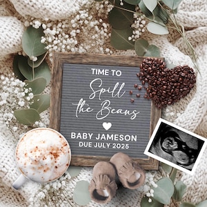 May include: A gray letter board with the text "Time to Spill the Beans" and a heart. Below the text is "Baby Jameson Due July 2025". There is a cup of coffee, a heart-shaped arrangement of coffee beans, a black and white ultrasound image, and a pair of brown baby booties.