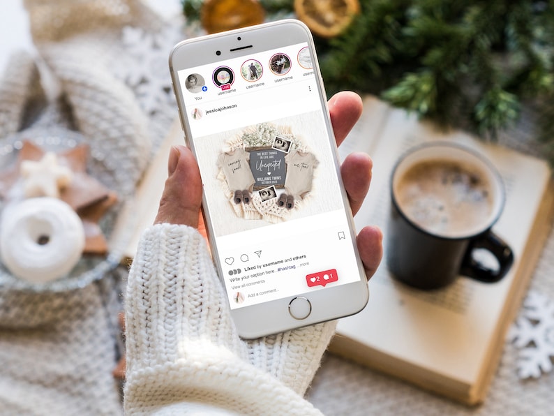 Pu&ograve; includere: Uno smartphone che mostra un post di Instagram con una foto di un annuncio di nascita. Il post presenta un cartello di legno con il testo "Le cose migliori della vita sono inaspettate. Amiamo i nostri gemelli." La foto &egrave; circondata da una ghirlanda di uncinetto bianca con due paia di minuscole scarpine per neonati.