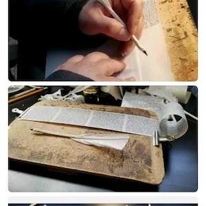 May include: A close-up of a person writing with a quill pen on a piece of paper. The paper is on a wooden surface. There are other pieces of paper and a quill pen on the surface.