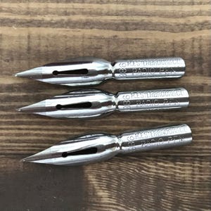 May include: Three silver fountain pen nibs with the text "COR. ESTERBROOK & CO. RADIO PEN" on each nib.
