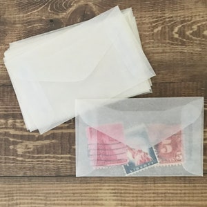 May include: A stack of white envelopes, some with a vintage look, and a single white envelope with three vintage stamps inside.