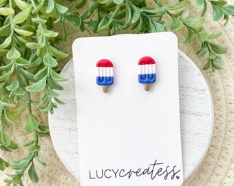 May include: A pair of red, white, and blue popsicle earrings on a white card with the text "LUCYcreates" in black.