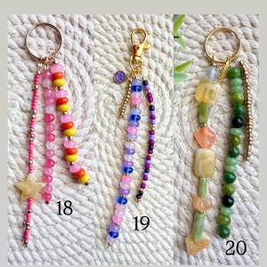 May include: Three beaded keychains with gold-colored hardware. One keychain features pink, yellow, and orange beads, and a star charm. Another has pink, blue, and purple beads. The third has green and yellow beads. Numbers 18, 19, and 20 are visible.