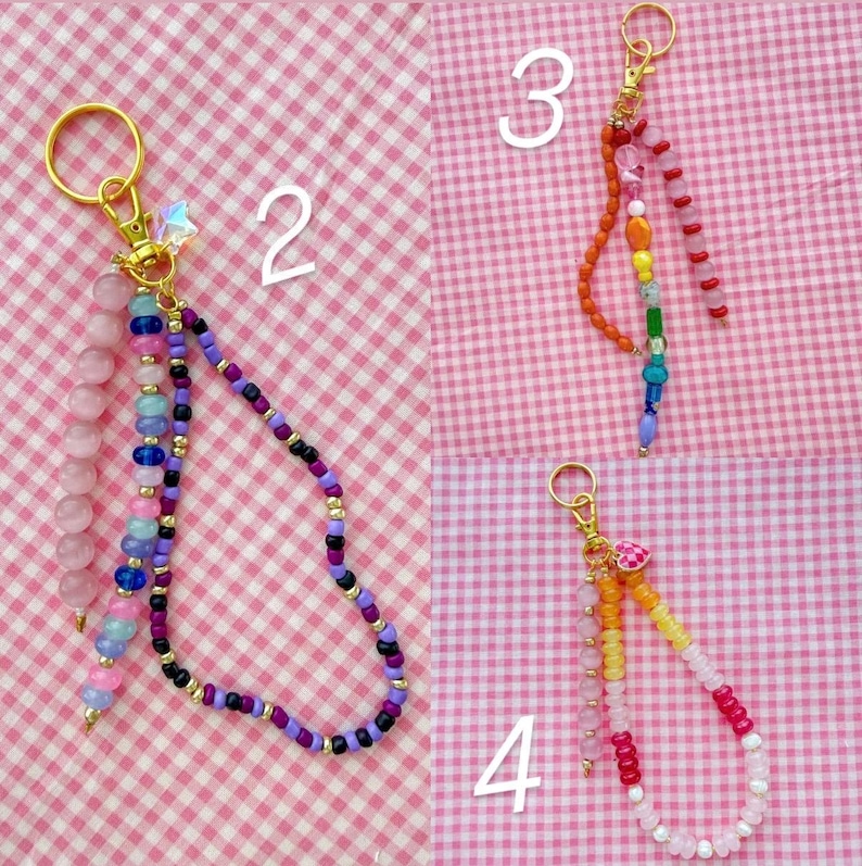 May include: Four beaded keychains with gold-colored hardware. Keychains feature various colors of beads, including pink, purple, blue, orange, and yellow. One keychain has a star charm. The keychains are on a pink and white checkered background.