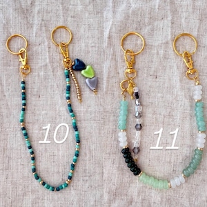 May include: Keychains with gold-colored hardware and beaded accents. One keychain features teal and gold beads, while another has a mix of green, white, black, and clear beads. The number "10" and "11" are printed on the image.