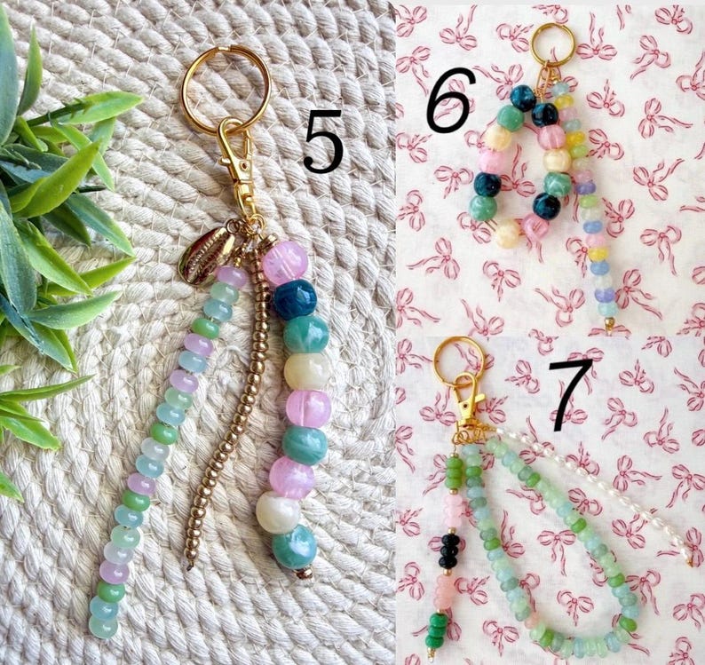 May include: Keychains with colorful beaded accents. One keychain features a gold-colored clasp, a small shell charm, and a strand of green, purple, and pink beads. Another has a strand of multi-colored beads. A third keychain has green and pink beads.