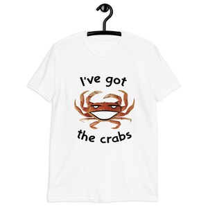 May include: White t-shirt with a black graphic of a crab with a smiling face and the text "I've got the crabs".