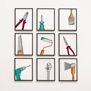 May include: Nine framed art prints showcasing hand-drawn illustrations of tools. The tools include pliers, a screwdriver, a paintbrush, a saw, a paint roller, needle-nose pliers, a drill, a wrench, and an axe. Each tool is depicted with colour accents.