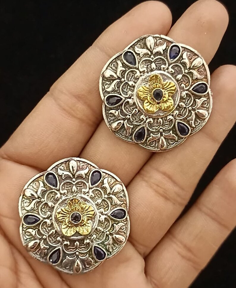 May include: A pair of silver and gold earrings with a floral design and blue gemstones.