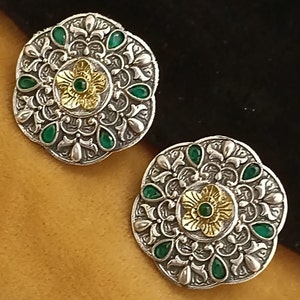 May include: A pair of silver earrings with intricate floral designs and green and gold accents.