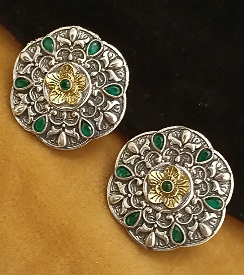 May include: A pair of silver earrings with intricate floral designs and green and gold accents.