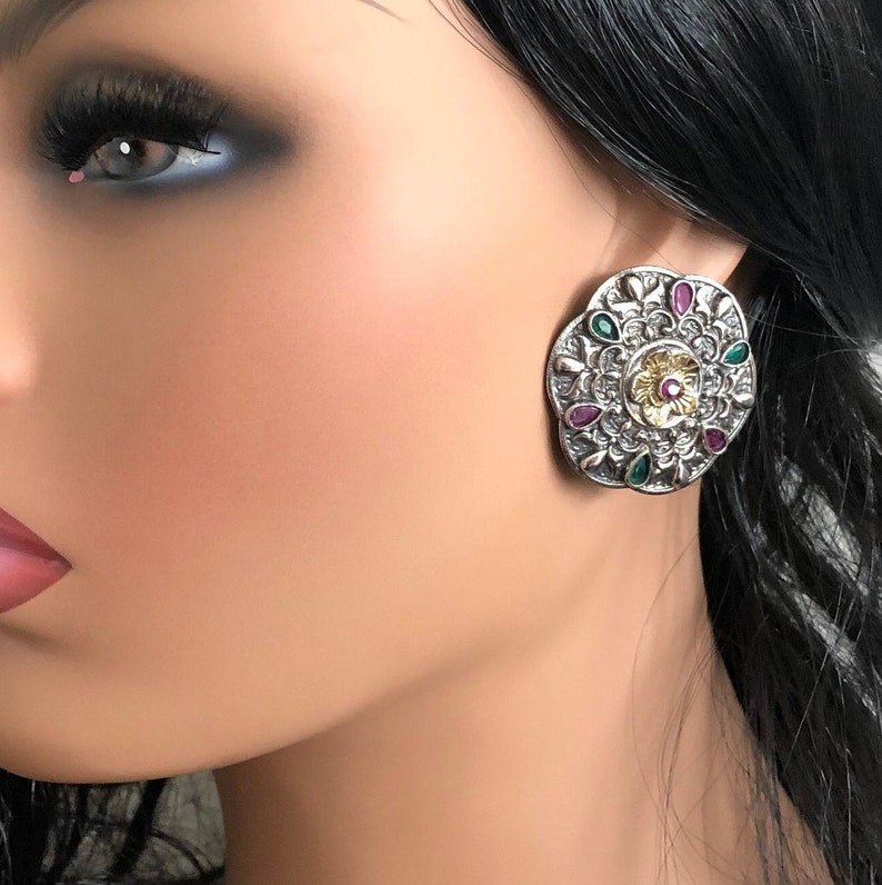 May include: Silver and gold tone earrings with a round design. The earrings are decorated with green, pink, and white stones.