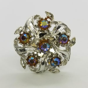 Peut inclure: Une bague en argent avec un motif floral et des pierres irisées. Les pierres sont un mélange de violet et d'orange.