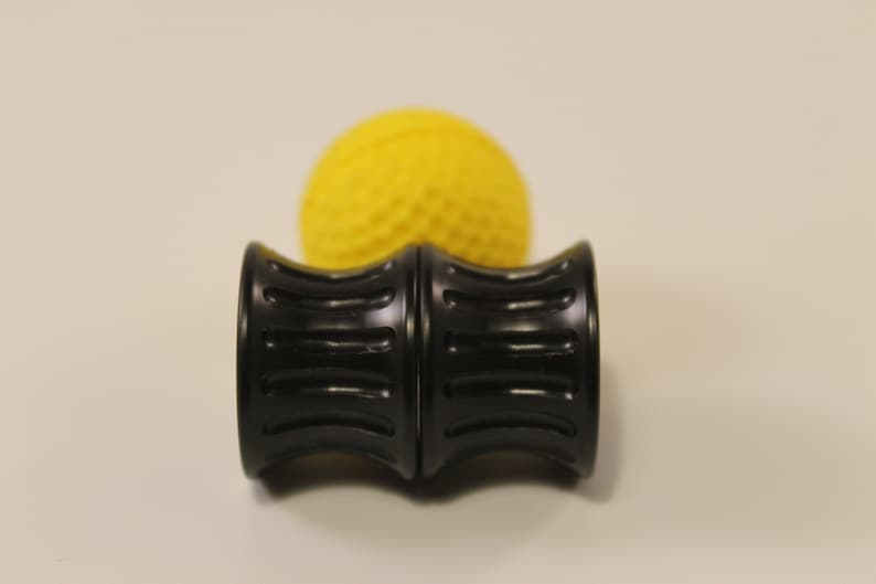 Peut inclure: Un rouleau en mousse noir avec une surface textur&eacute;e. Le rouleau est compos&eacute; de deux pi&egrave;ces reli&eacute;es. Une balle textur&eacute;e jaune est derri&egrave;re le rouleau.