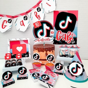 May include: A collection of party decorations featuring a TikTok theme. Includes a cake, cupcakes, gift boxes, and a banner with the TikTok logo and the name "Gabi". The color scheme is red, black, white, and blue.