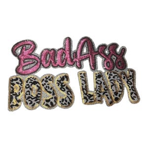 May include: Sequin iron-on patch with the text "BadAss Boss Lady" in pink, gold, and black with a leopard print design.