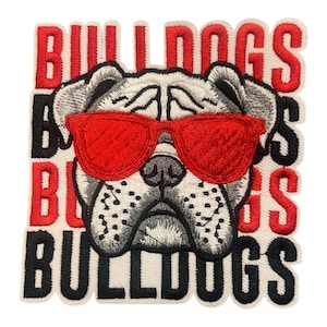 May include: Embroidered patch featuring a bulldog wearing red sunglasses. The word "BULLDOGS" is stacked vertically in red and black letters, surrounding the dog's face. The patch has a white background.
