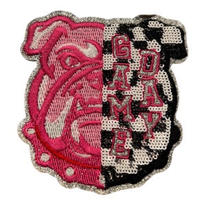 May include: Embroidered patch with a split design. One side features a pink bulldog graphic, the other a black and white checkered pattern with the text "GAMA MAY". The patch is outlined in silver.