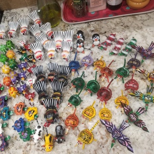 May include: A collection of colorful, hand-painted wooden animal figurines. The figurines are made in a variety of shapes and sizes, and they are all decorated with intricate details. Some of the animals include a bird, a turtle, a fish, a deer, and a frog.
