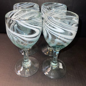 May include: Set of four clear glass wine glasses with white swirl designs.
