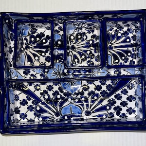 May include: A blue and white ceramic serving tray with four compartments. The tray has a decorative floral pattern with gold accents.