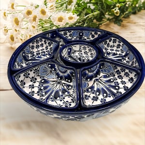Könnte beinhalten: Eine blaue und weiße Keramik-Servierplatte mit sechs Abschnitten und einer zentralen Dip-Schale. Die Platte ist mit einem floralen Muster mit blauen und weißen Akzenten verziert.