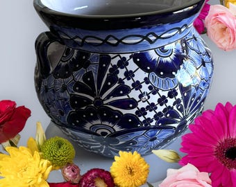Può includere: Un vaso in ceramica blu e bianca con un motivo floreale. Il vaso ha due manici e una bocca larga. È decorato con un motivo tradizionale messicano Talavera.