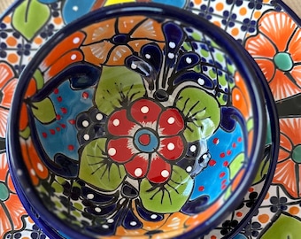 May include: A set of two ceramic bowls with a colourful floral pattern in shades of blue, green, red, orange, and yellow. The bowls are nested together, with the smaller bowl on top.