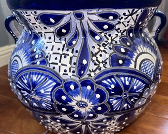 Può includere: Un grande vaso in ceramica blu e bianca con intricati disegni floreali. Il vaso ha due manici e un'ampia apertura rotonda.