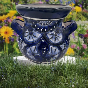 May include: A blue and white ceramic planter with a floral design. The planter has two handles and a wide mouth.