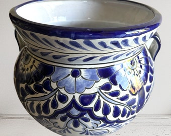 Può includere: Un vaso in ceramica bianca con disegni floreali blu e bianchi. Il vaso ha due manici e un'ampia apertura.