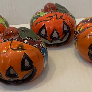 Può includere: Quattro figurine di zucca in ceramica con dettagli dipinti. Ogni zucca ha un design diverso e presenta un viso di zucca intagliato.