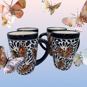 May include: Four blue and white ceramic mugs with orange butterfly designs. The mugs have a white background with blue and white floral patterns and orange butterflies.