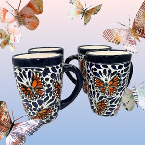 May include: Set of four blue and white ceramic mugs with orange butterfly designs. The mugs have a glossy finish and are perfect for everyday use.