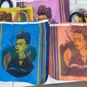 May include: Four colorful mesh tote bags with a Frida Kahlo portrait design. Each bag features a different color background and a unique Frida Kahlo image. The bags have white straps and are made of a lightweight, breathable material.