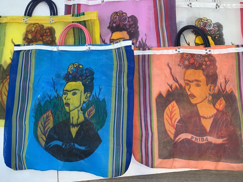 May include: Four colorful mesh tote bags with a Frida Kahlo portrait design. Each bag features a different color background and a unique Frida Kahlo image. The bags have white straps and are made of a lightweight, breathable material.