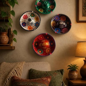 May include: Four circular ceramic wall plates shaped like miniature sombreros, each featuring a unique hand-painted floral pattern in vibrant colors including green, white, black, and red, arranged in a diamond formation on a wall.