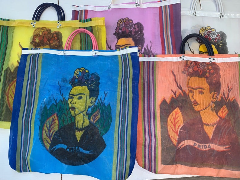 May include: Four colorful mesh tote bags with a Frida Kahlo design. Each bag has a different color background and features a portrait of Frida Kahlo with the word "Frida" written on a banner.
