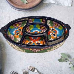 以下が含まれることがあります： 青、緑、オレンジ、赤、黄色の花柄で飾られた、6つの個別コンパートメントが付いたカラフルなセラミック製サービングディッシュ。ディッシュは青い縁取りと白い背景をしています。
