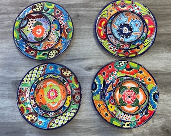 May include: Set of four colorful ceramic dinner plates with intricate floral designs. Each plate features a smaller plate in the center, creating a nested effect. The plates are decorated with vibrant colors, including red, blue, green, yellow, and orange.