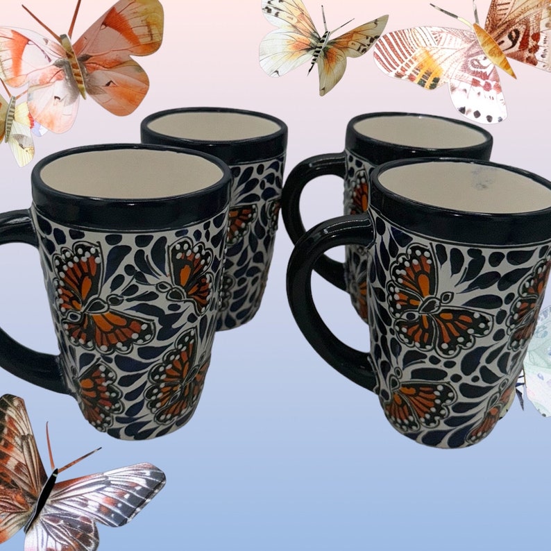 May include: Set of four blue and white ceramic mugs with a butterfly design. The mugs have a black rim and a handle. The butterflies are orange and black.