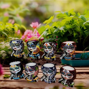 Op de afbeelding: Acht kleurrijke keramische mokken met schedelontwerpen van Día de Muertos. Elke mok heeft een ander schedelontwerp met ingewikkelde details en levendige kleuren.