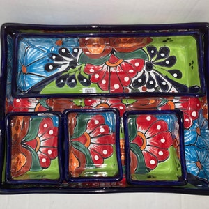 May include: A blue and white ceramic serving tray with four smaller compartments. The tray and compartments feature a colorful floral design with red, green, blue, and white flowers.