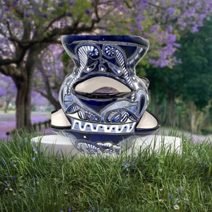 Puede incluir: Un macetero de cerámica azul y blanco con intrincados diseños florales. El macetero está hecho en un estilo tradicional mexicano y tiene un diseño único de tres niveles.