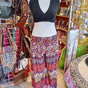 May include: A black halter top with a deep V-neckline and a pair of colourful printed palazzo pants. The pants have a white background with red, blue, yellow and purple patterns.