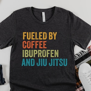 Angetrieben durch Kaffee Ibuprofen und Jiu Jitsu T-Shirt für Männer und Frauen - Lustiges Martial Arts Graphic Tee - Perfekte BJJ Geschenkidee