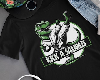 May include: Black t-shirt with a green cartoon dinosaur wearing a white karate uniform and kicking. The dinosaur is in a circle with the text "Kick a Saurus" in green letters.