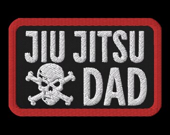 May include: Black and white embroidered patch with a skull and crossbones and the text "Jiu Jitsu Dad" in white lettering. The patch has a red border.